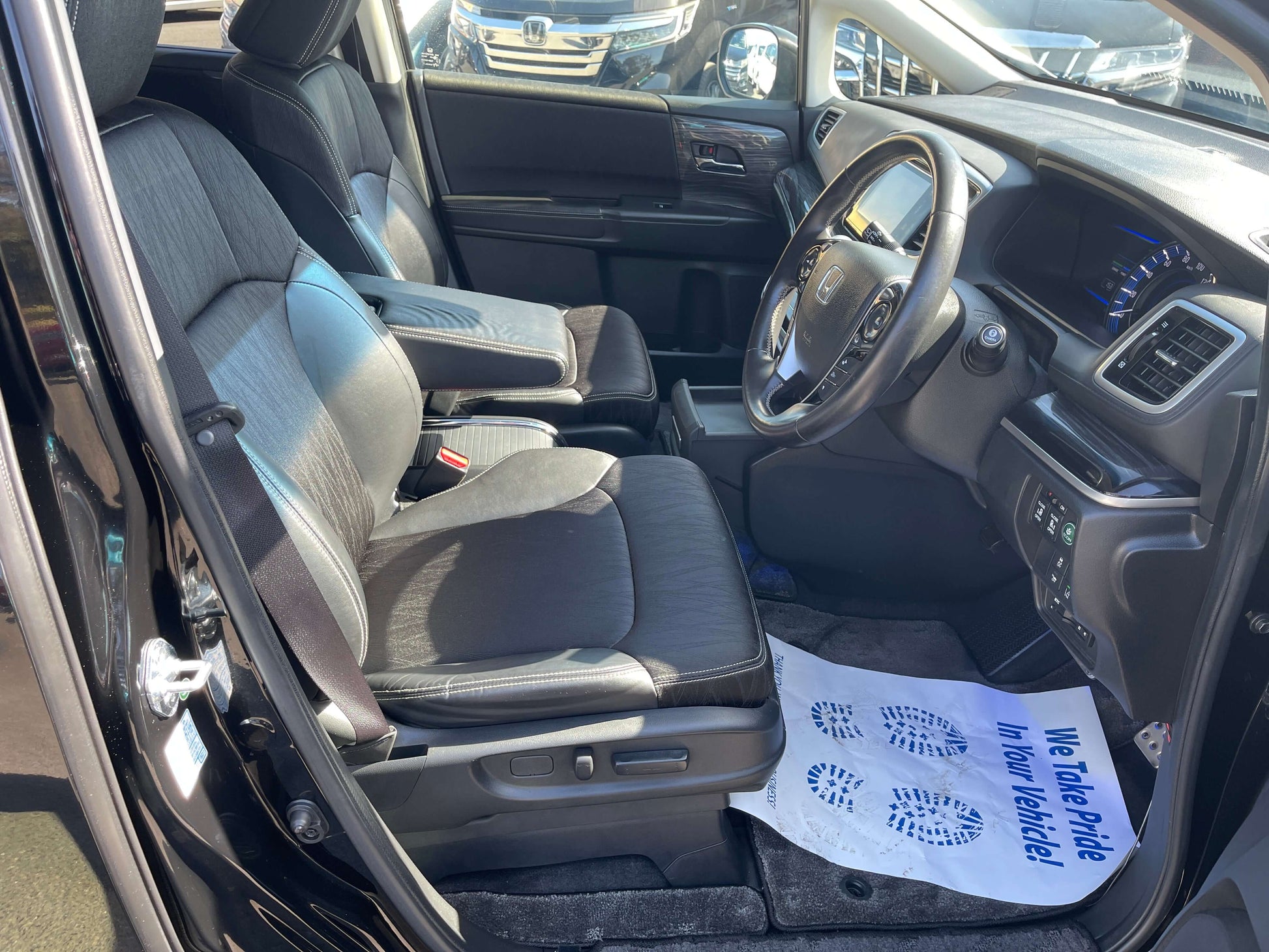 Interior view of a 2016 Honda Odyssey 2.0 Hybrid showcasing front seats and dashboard with modern design.