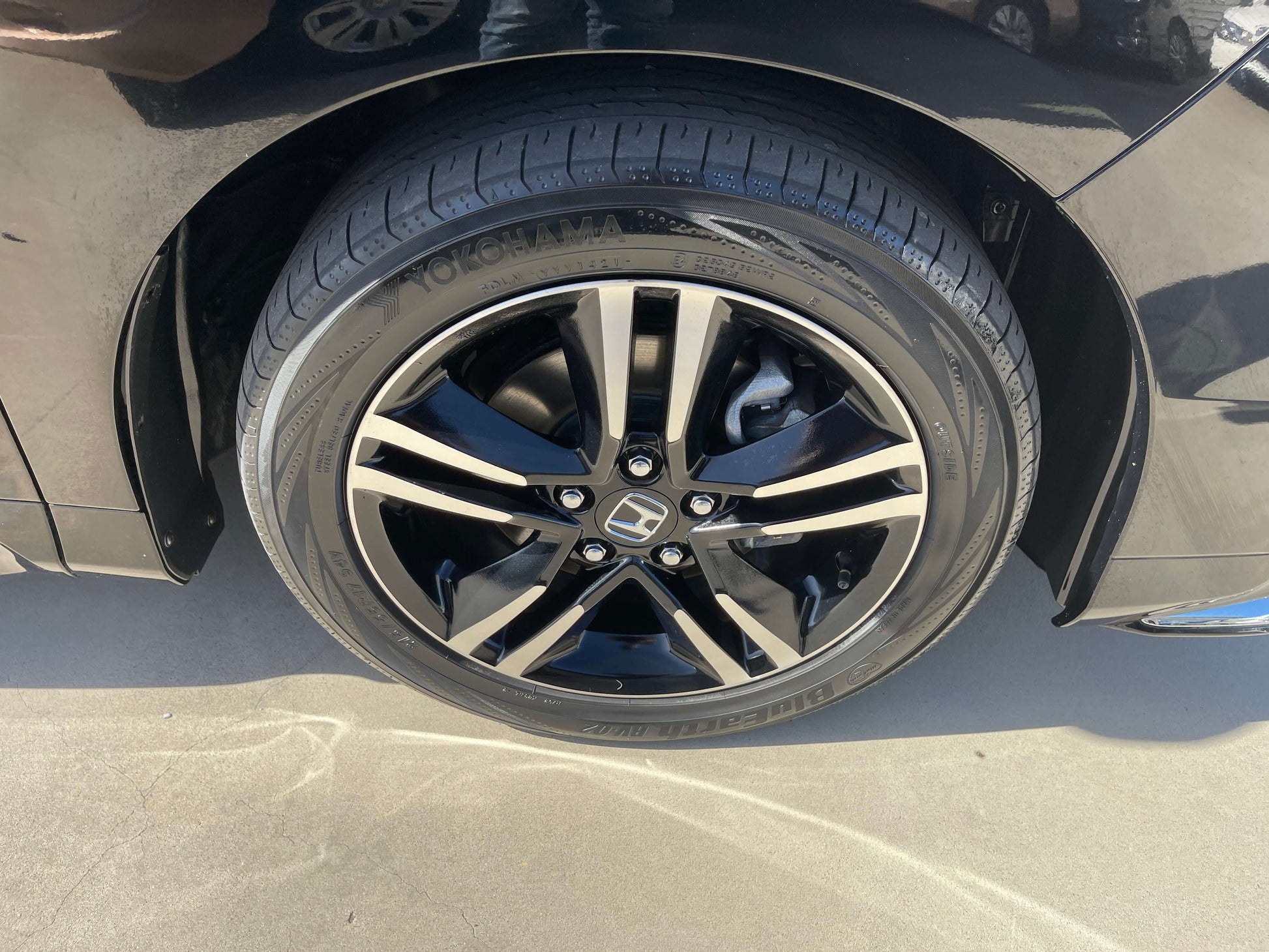 Wheel of a 2016 Honda Odyssey 2.0 Hybrid showing black alloy rims and tire.