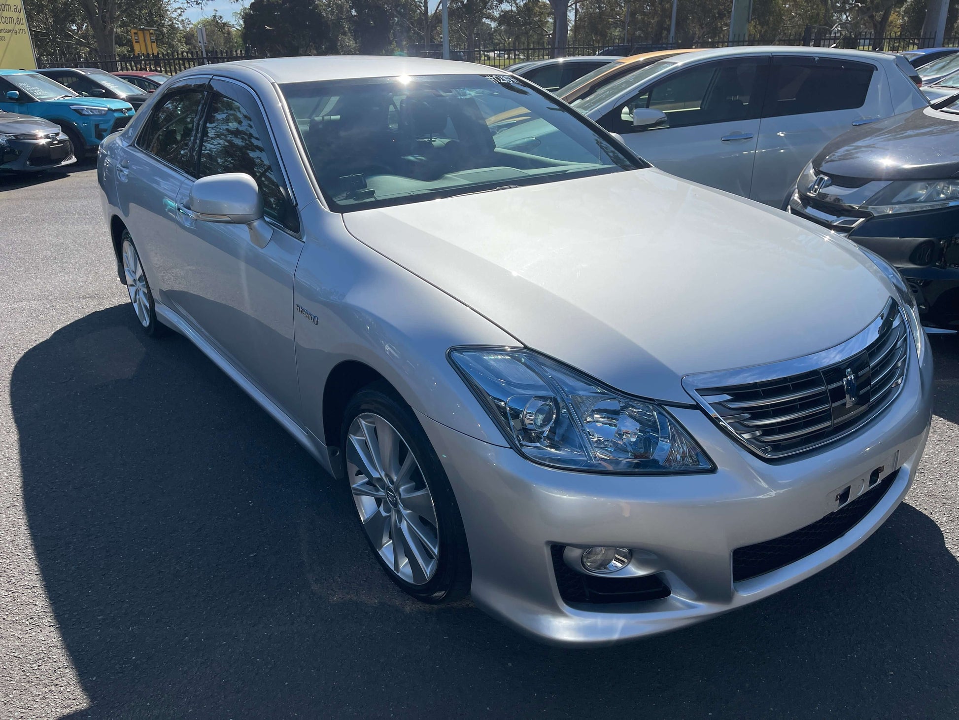 2009 Toyota Crown V6 3.5L Hybrid Luxury Sedan in silver color, parked among other cars.