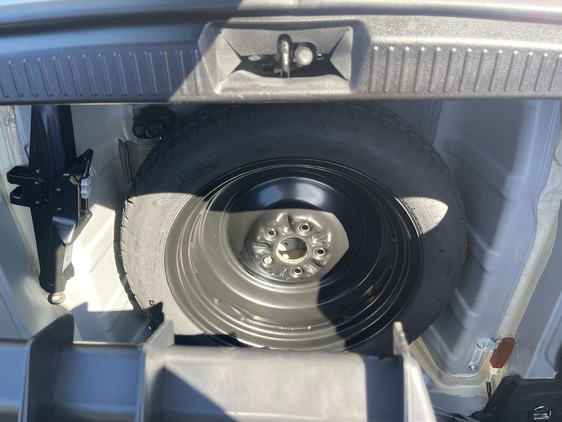 2009 Toyota Crown V6 3.5L Hybrid Spare tire and jack stored in the trunk of a vehicle, showcasing the interior storage design.