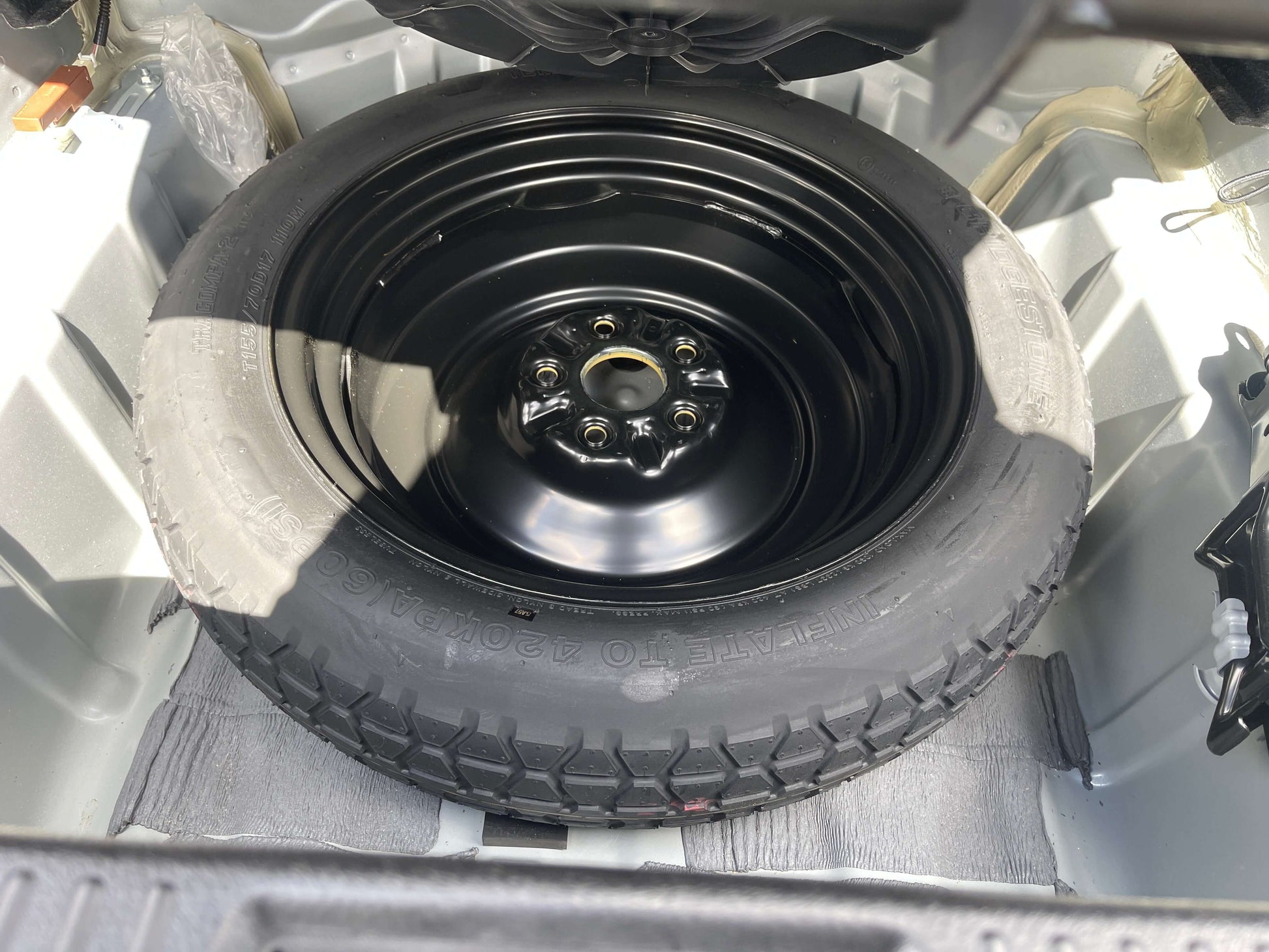 2009 Toyota Crown V6 3.5L Hybrid Spare tire inside the trunk of a vehicle, featuring a black wheel with a tire in good condition.